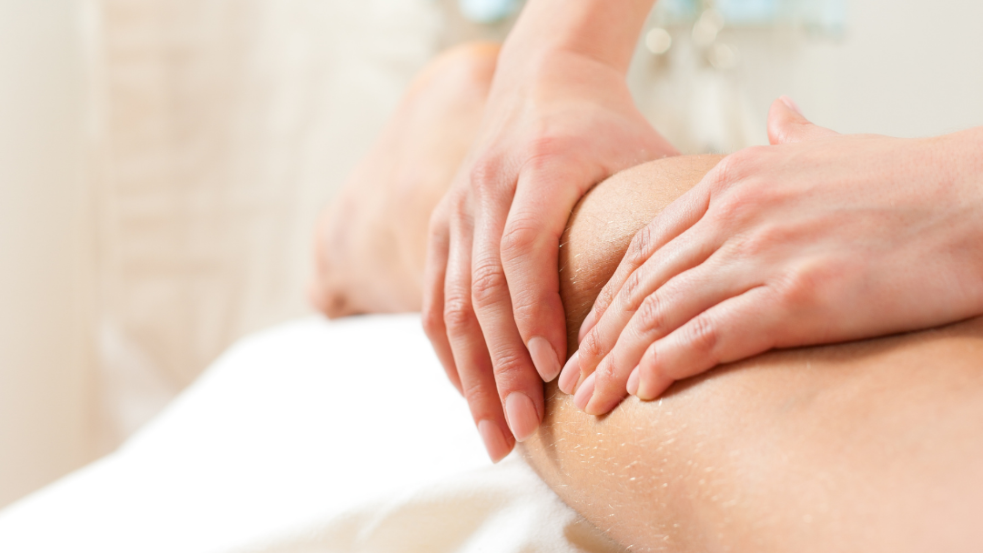 Fisioterapeuta da Fisiome realiza atendimento domiciliar em Boa Viagem, Recife, aplicando suavemente técnicas de mobilização articular no ombro de uma paciente sentada confortavelmente em sua sala de estar.